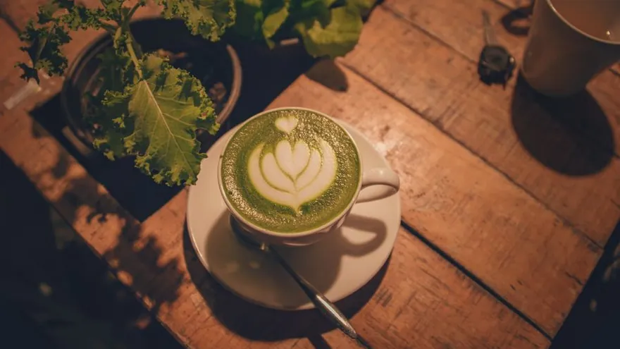A cup of matcha latte with leaf latte art on top