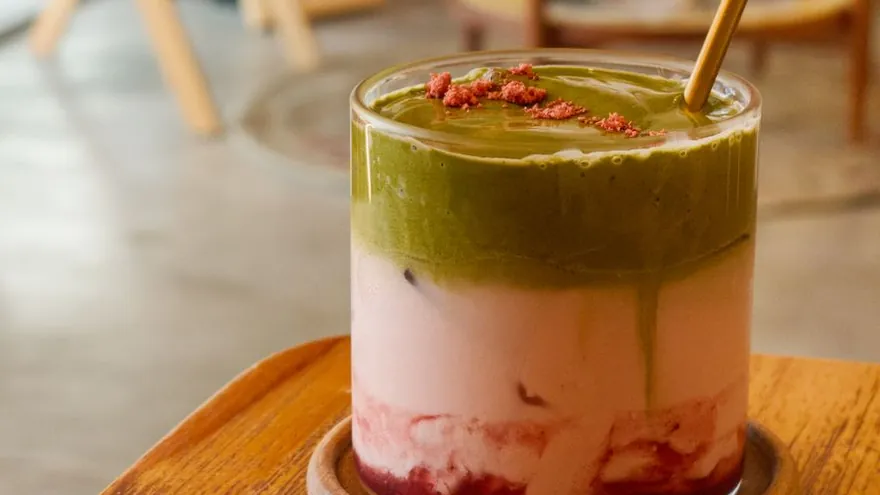A glass of strawberry matcha with a pink layer under a green layer